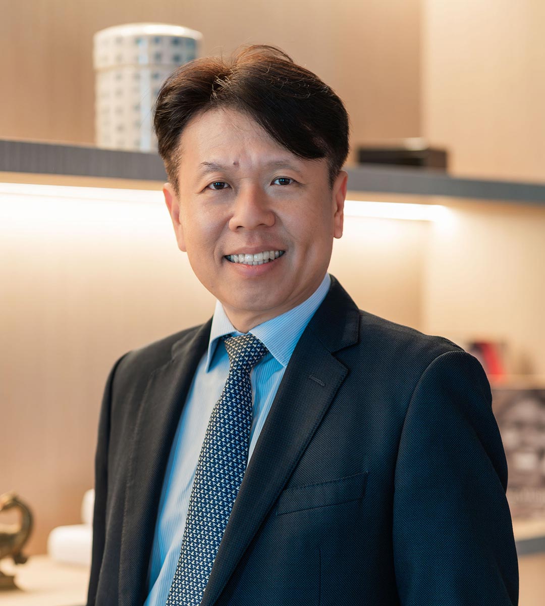 Andrew Chia, in suit, in a warmlt-liy area, portrait-view.