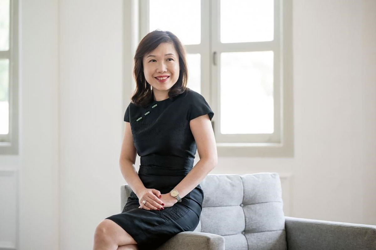 Joy Lim, in black dress, seated cross-legged.
