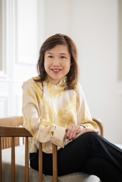 Joy Lim, in yellow dress, seated and looking to the left slightly.