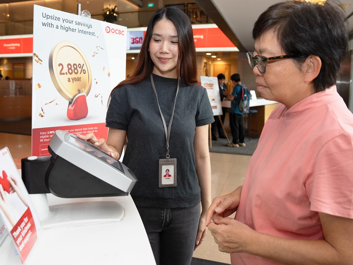Siti Hatijah, helping a bespectacled woman at work.
